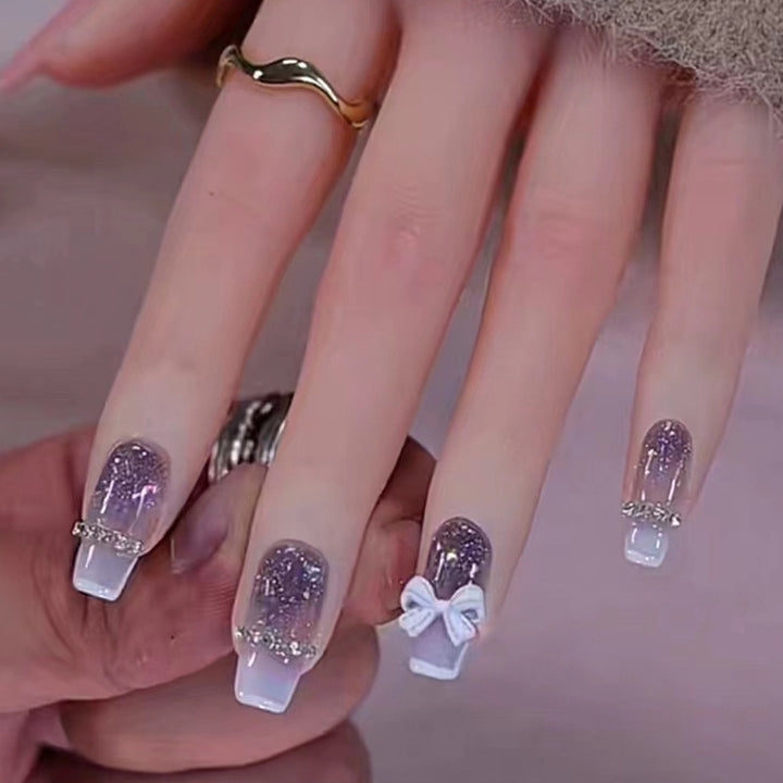 Long-length ballet-style nail chain with diamond-studded bow-shaped embellishment nail art
