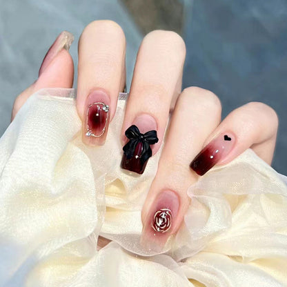 Black bow-shaped rhinestone decoration on the nails of the tea flower style nails