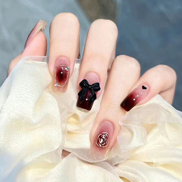 Black bow-shaped rhinestone decoration on the nails of the tea flower style nails