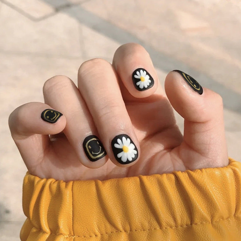 Black-colored small daisy smiling face manicure